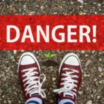 Cette image représente un sol avec un encart rouge marqué danger et des chaussures types basket, puis une jeune pousse devant ces dernières. Ceci est la bannière d'un article de blog : rédigé par EcoVerde Parcs et Jardins pour illustrer les plantes dangereuses pour la santé des hommes et des animaux.